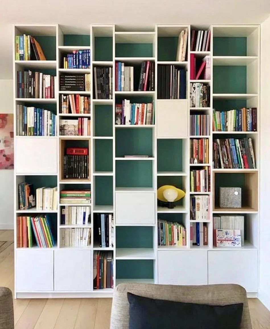 Bibliothèque sur mesure pleine hauteur, cases blanches sur fond vert, garnie de livres