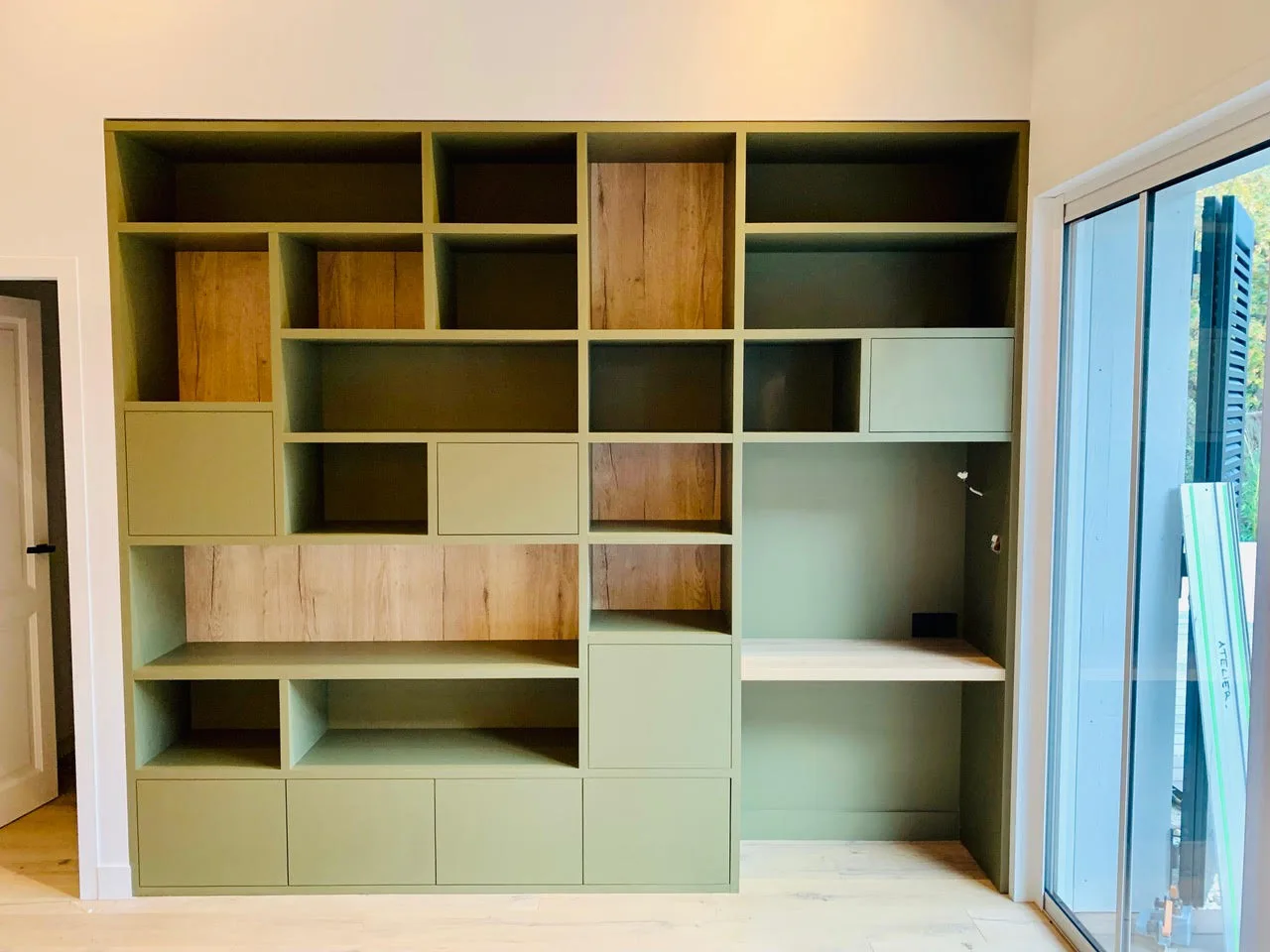 Grande bibliothèque sur mesure vert sauge et chêne avec bureau intégré