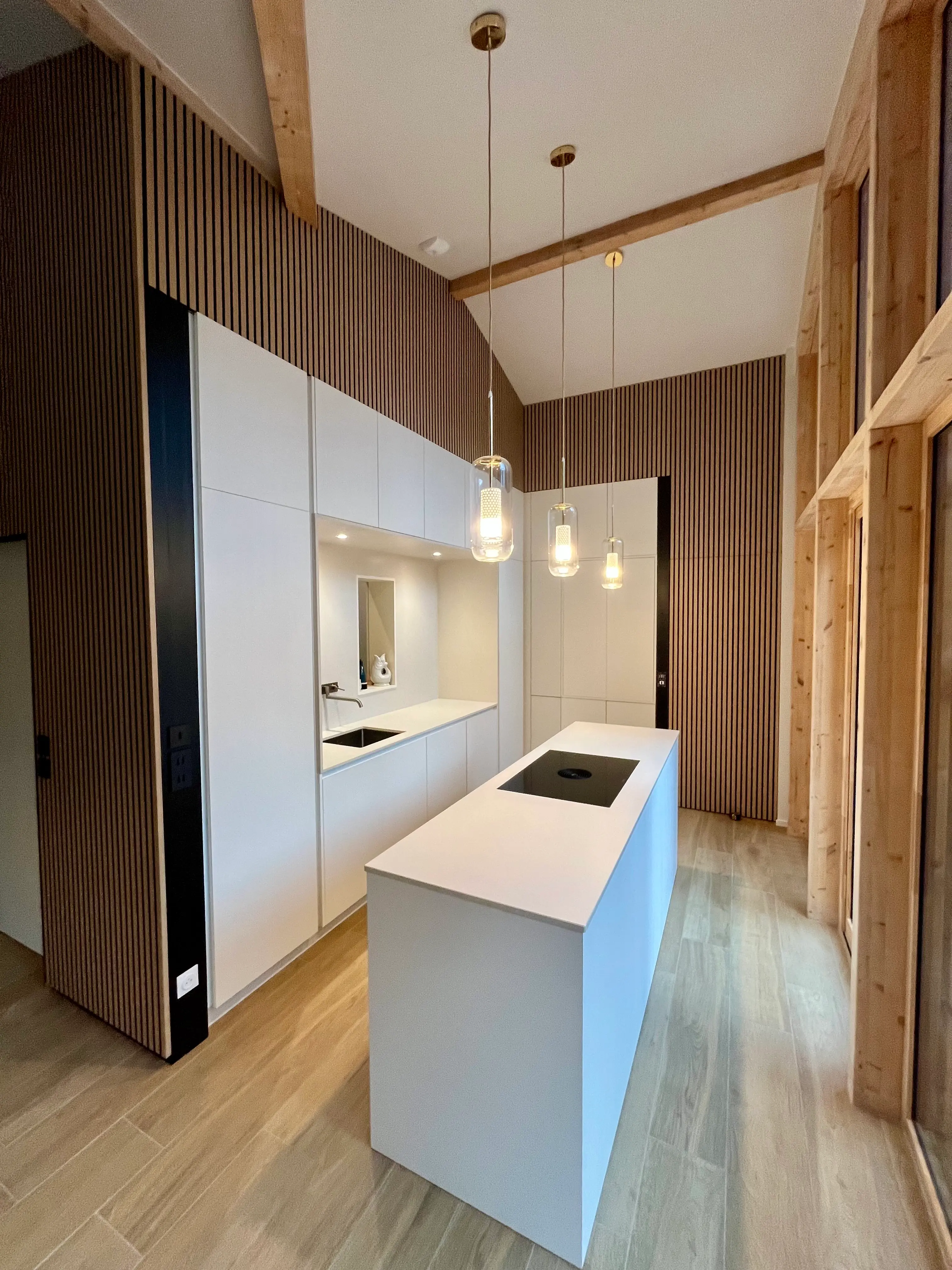 Cuisine sur mesure blanche, îlot et mur en tasseaux de bois