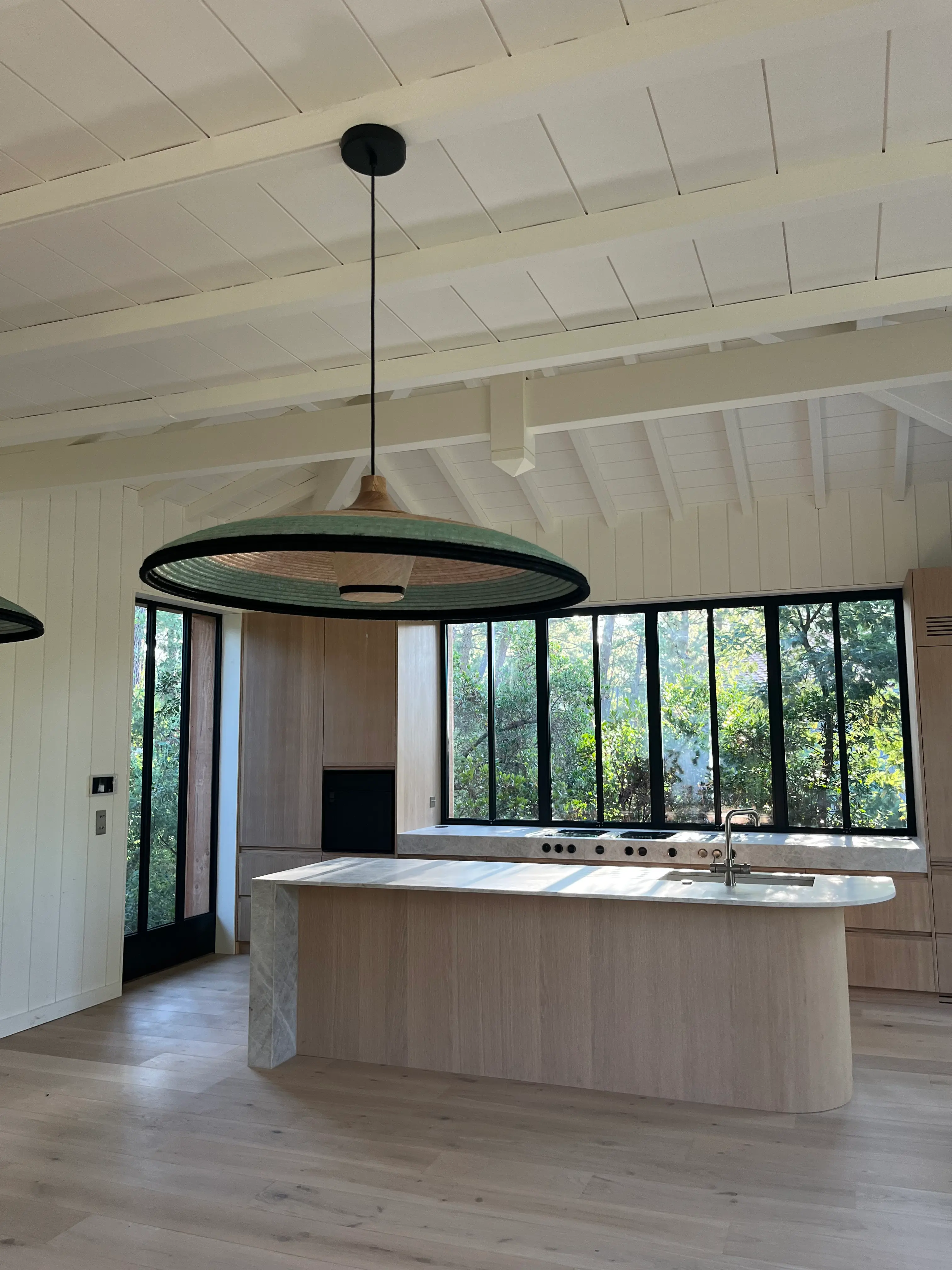Cuisine sur mesure chêne clair, îlot pierre, baies sur forêt, esprit bassin