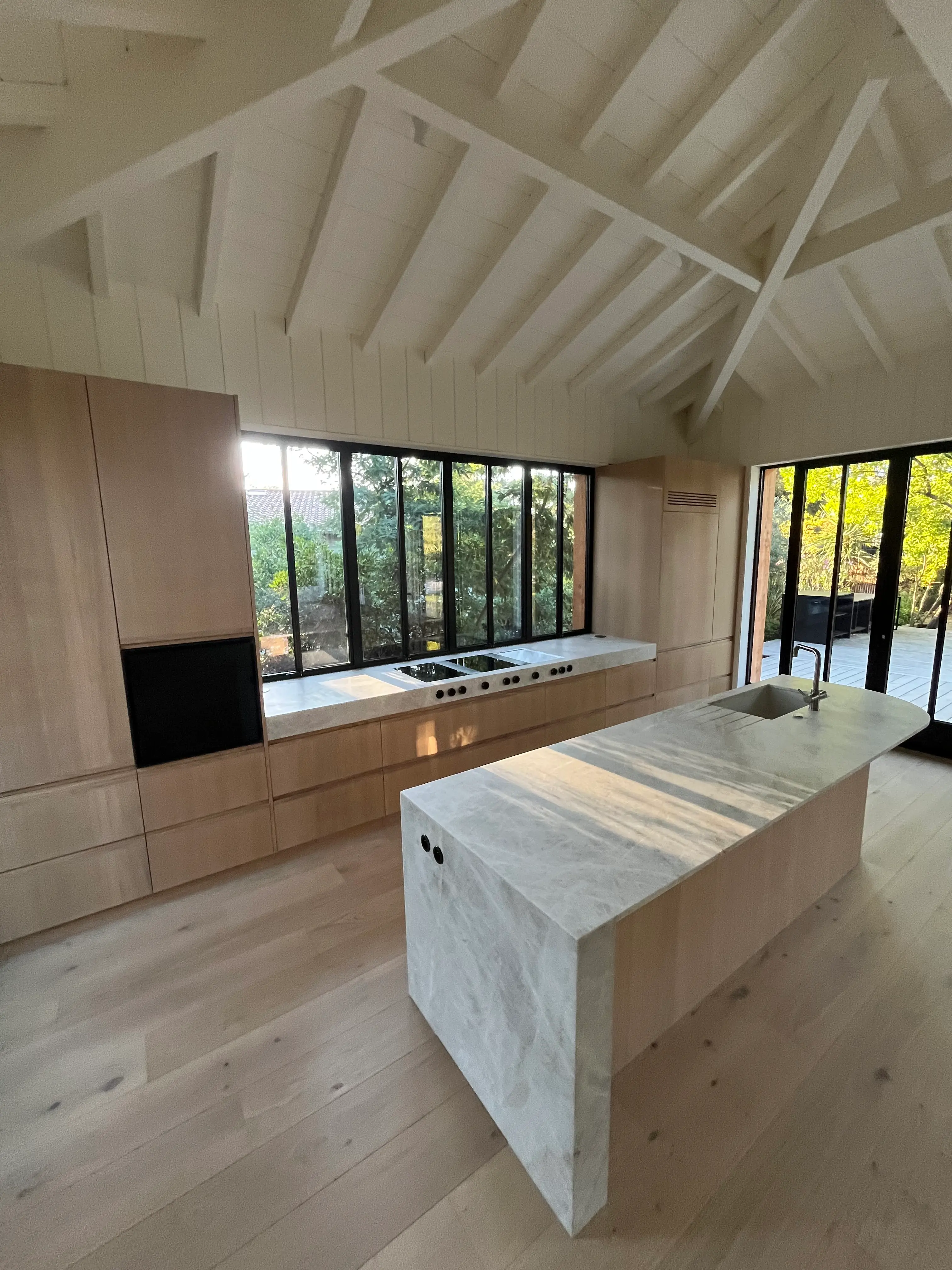 Cuisine sur mesure chêne clair, îlot pierre, baies sur forêt, esprit bassin