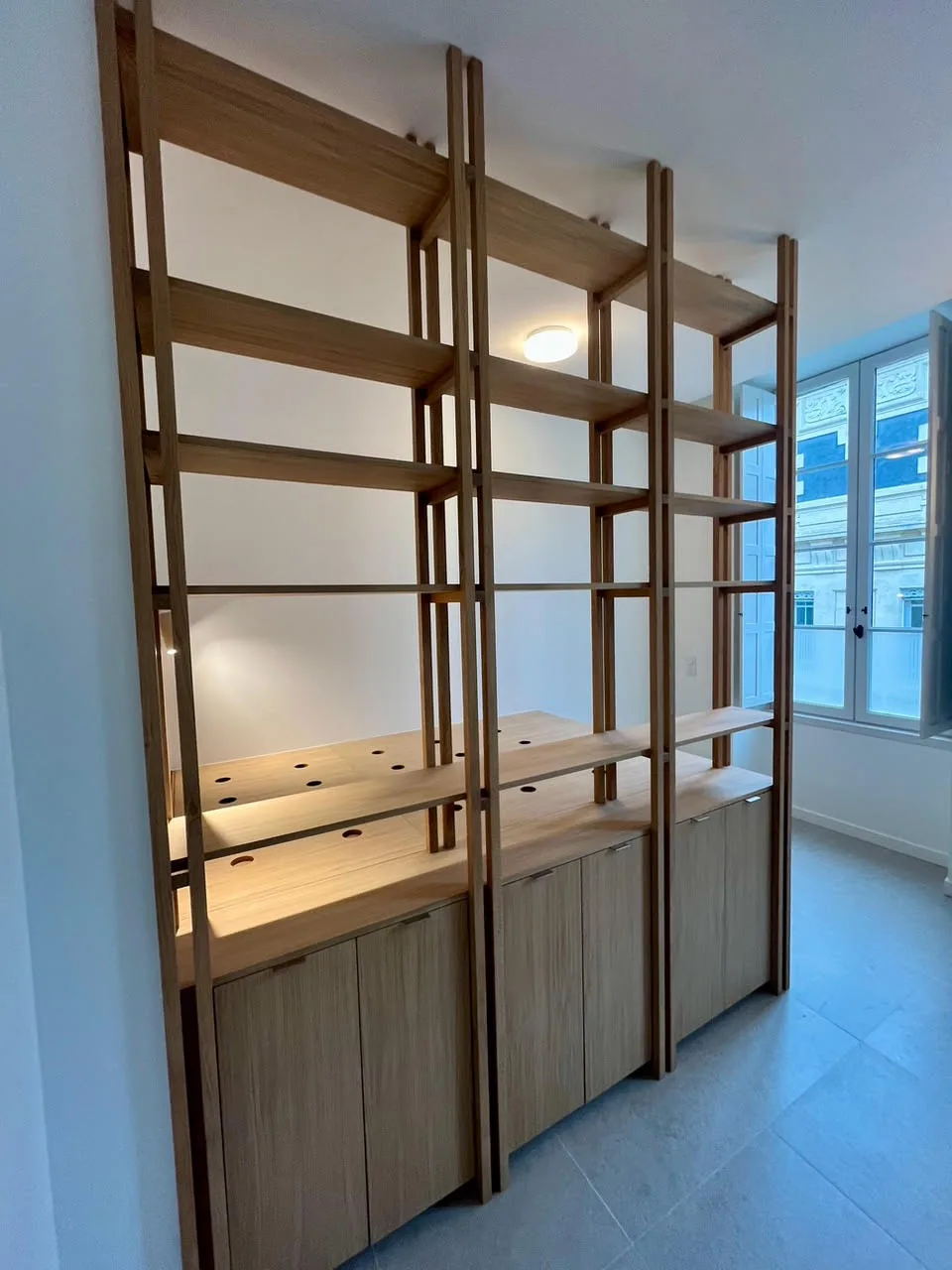 Étagères en bois sur montants claustra devant une fenêtre, sur mesure