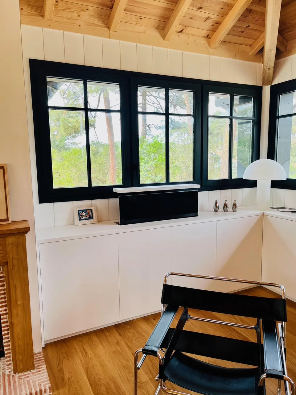 Meuble TV bas sur mesure avec téléviseur escamotable, façades blanches sous fenêtres noires, esprit bassin