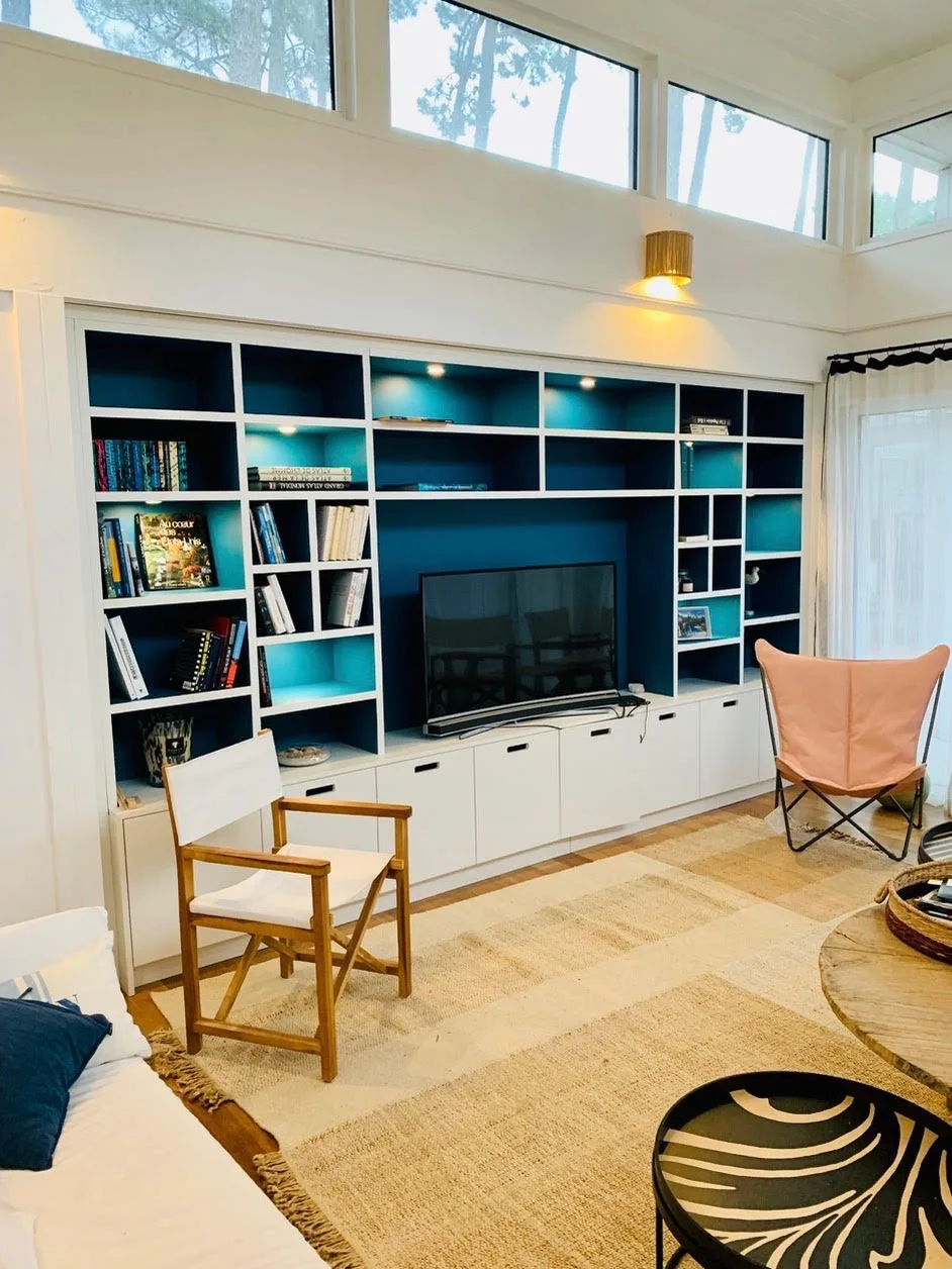 Bibliothèque et meuble TV sur mesure, fond bleu et niches éclairées, salon