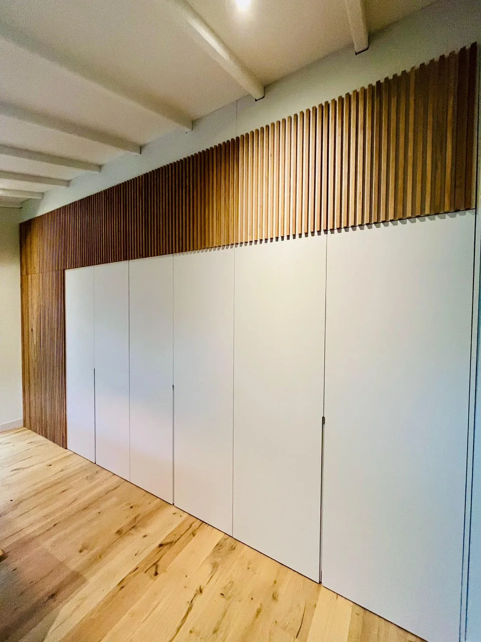 Placards muraux blancs pleine hauteur avec bandeau en tasseaux de bois, sur mesure
