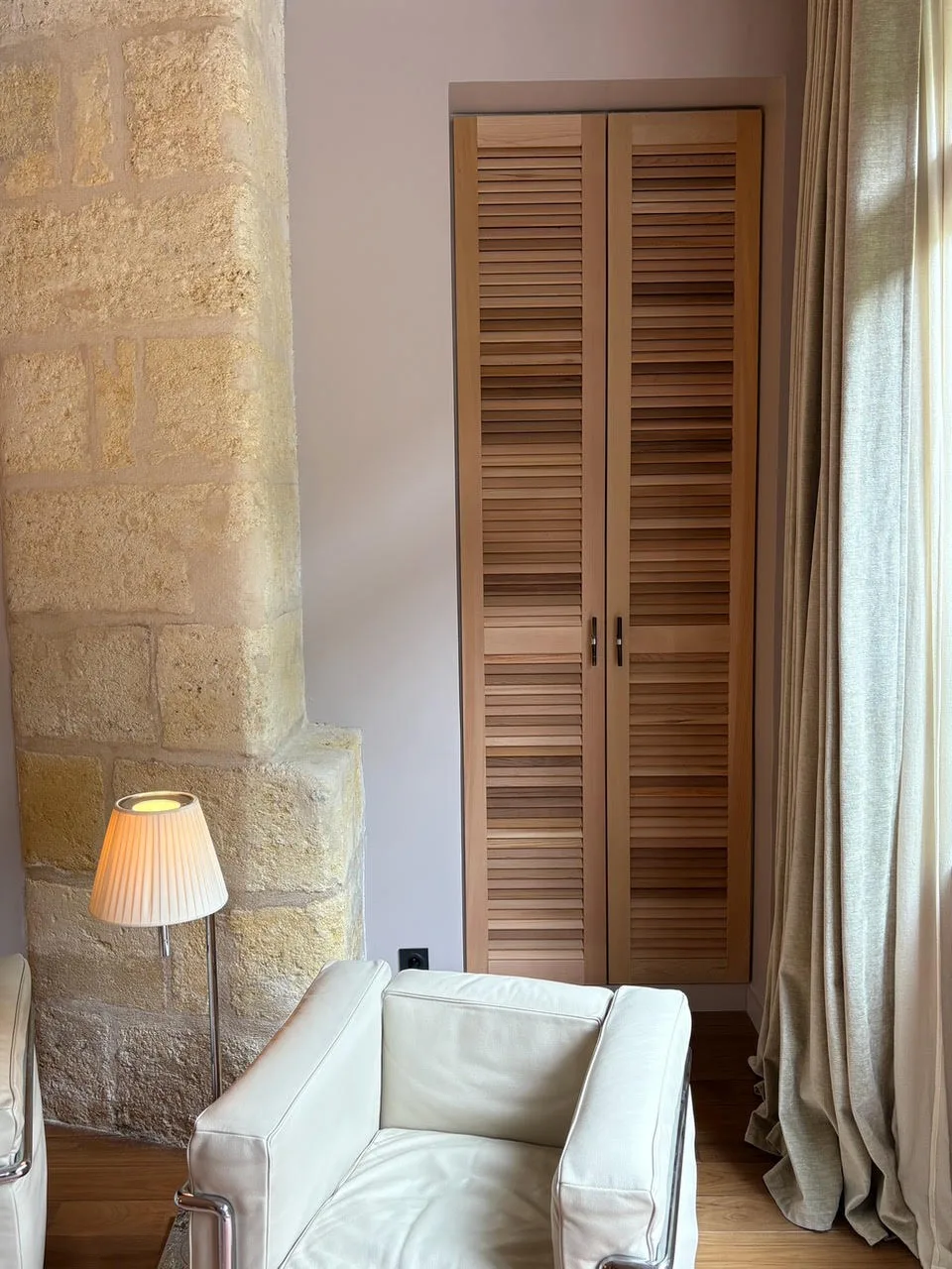 Placard sur mesure à portes persiennes en bois, intégré près d'un mur en pierre